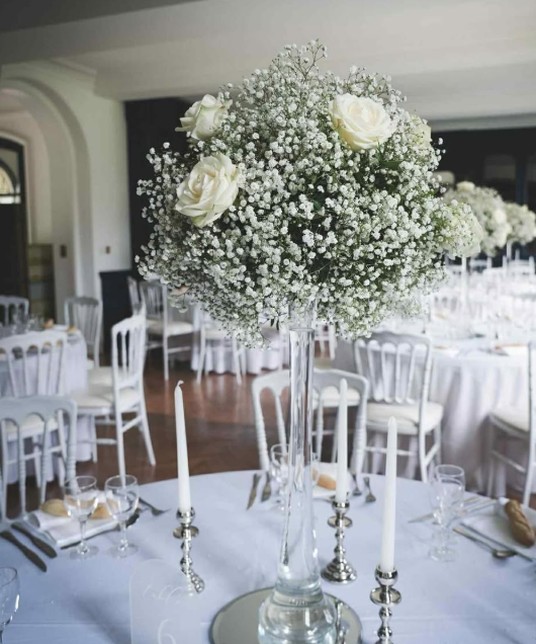Reception table, centrepiece of gypsophila and white roses, white chairs