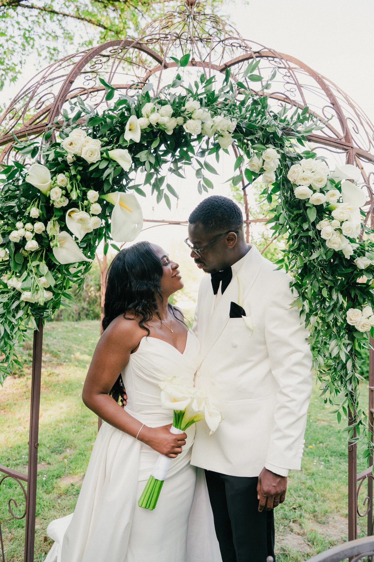 Couple under an arch of white flowers