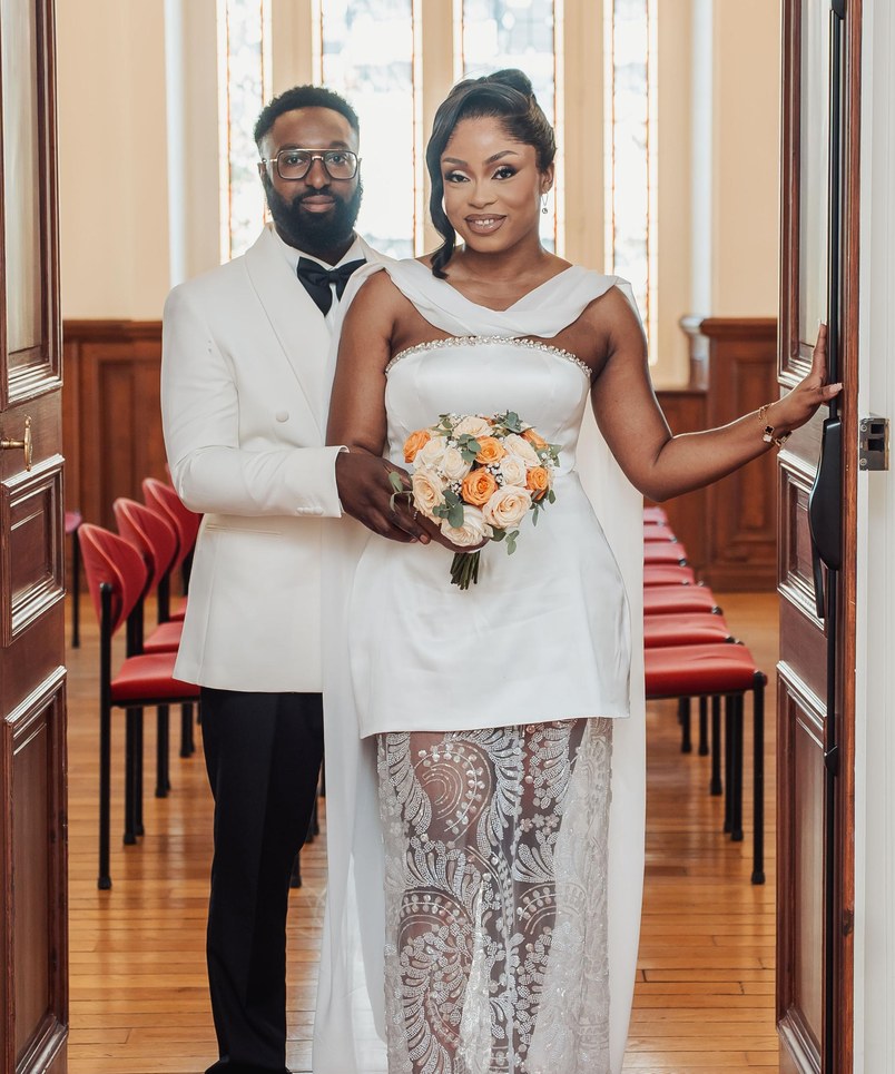 Axelle and Steve at the town hall, in white outfits, orange and cream bouquet
