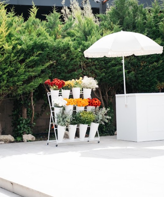 Flower bar: buckets of fresh flowers on a stand, white parasol