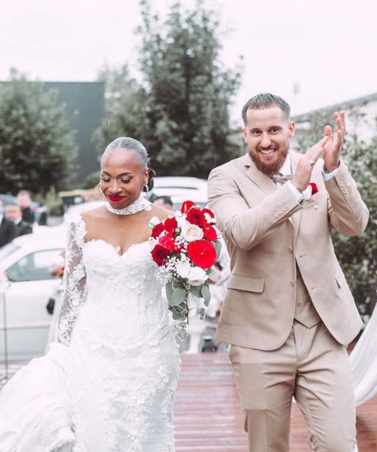 Déborah and Maxime clapping on the flower-lined aisle after the ceremony