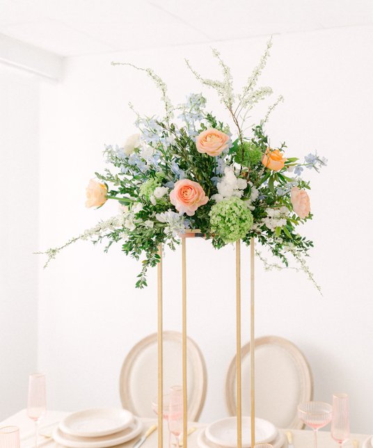 Centrepiece on a golden pedestal, pastel flowers and greenery
