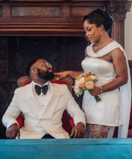 Couple en tenue blanche, assis dans un fauteuil rouge