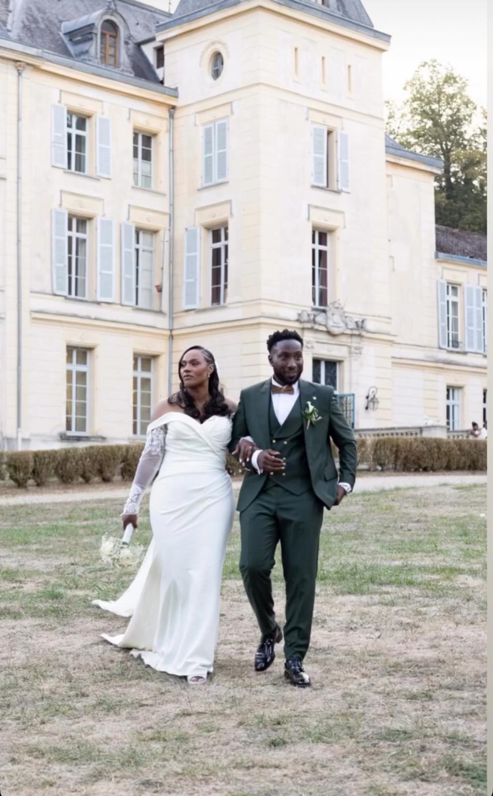 Ingrid and Popo walking in front of a château, the groom in a green suit