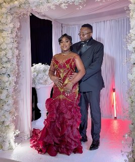 Couple devant une arche de fleurs blanches, robe rouge