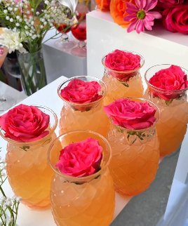 Roses fuchsia dans des verres ananas, cocktail orange