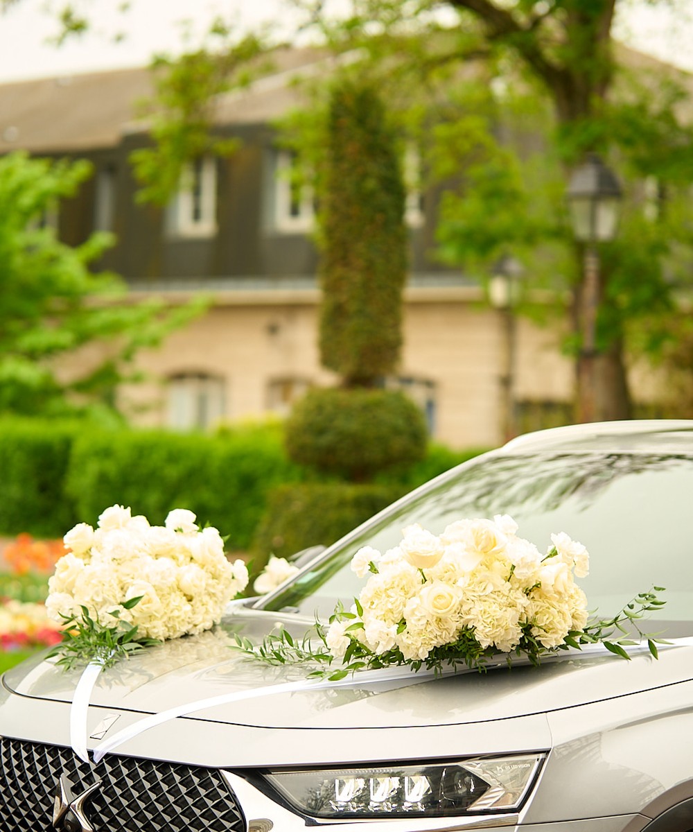 Wedding car decorated with bouquets of white roses and ribbons